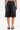 A person stands facing away, wearing the STARS SHINING RHINESTONE BERMUDA SHORT—high-waisted with frayed hems and back pockets—paired with black sandals. Only the lower back and legs are visible against a plain white background.