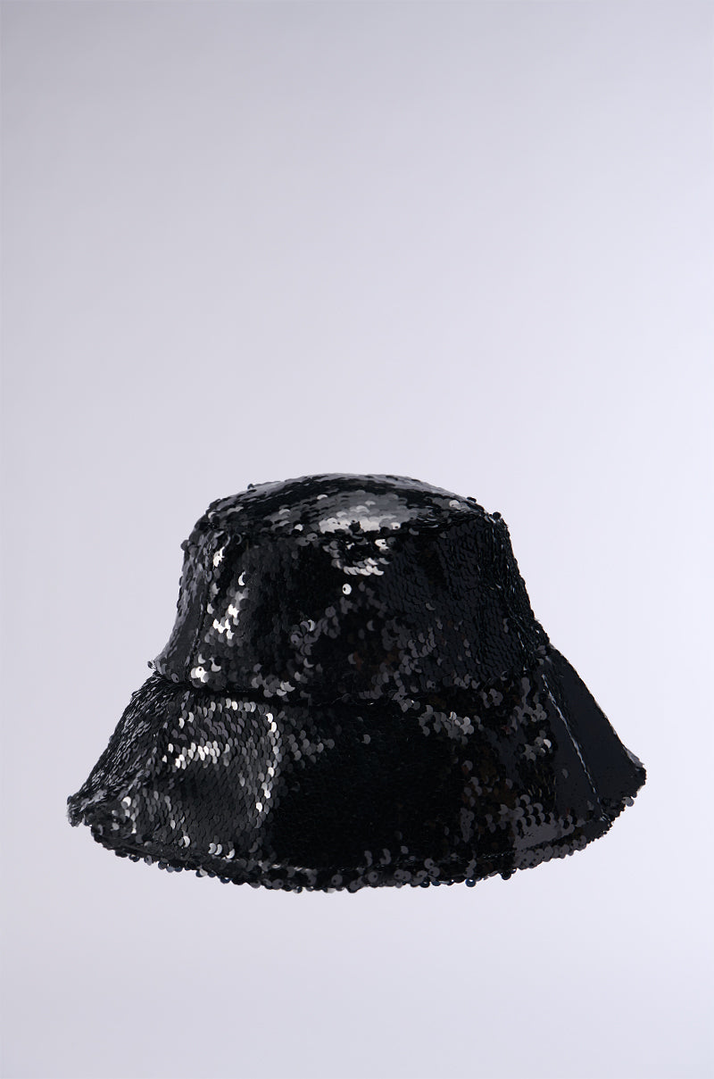 Introducing the TIME TO SHINE SEQUIN BUCKET HAT IN BLACK, adorned with reflective black sequins that create a shimmering effect. This fashionable hat boasts a rounded crown and a downward-sloping brim, elegantly showcased against a plain light gray background.