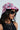 A person wearing the $100 "Money on My Mind" bucket hat with a collage pattern, dark sunglasses, and a black top. They have long dark hair and a silver necklace with assorted pendants against a plain light background.