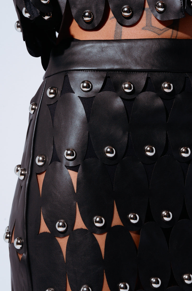 Close-up view of the black Sneak Peek Studded PU Midi Skirt featuring circular cutouts and silver studs. The unique geometric pattern creates an edgy, modern look, highlighting a focus on alternative or high-fashion styling.