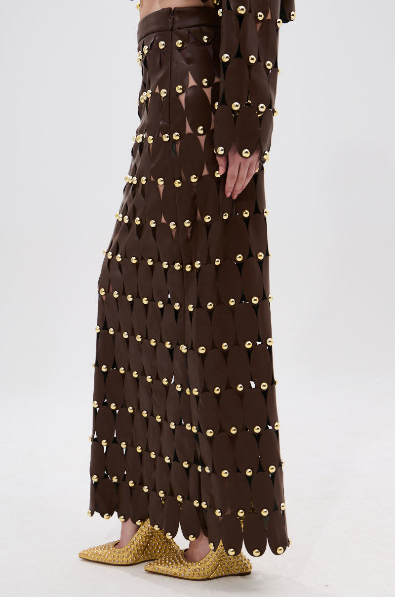 A person wears the Sneak Peek Studded PU Midi Skirt in Brown with pointed gold studded shoes. Only their lower body is visible against a plain background.