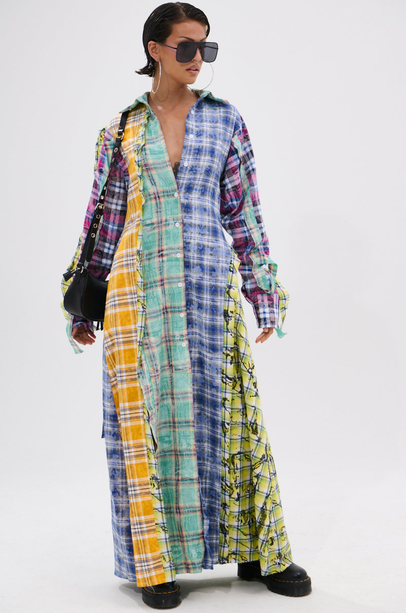 Model wears the STAR OF THE SHOW PLAID MAXI DRESS, a patchwork plaid maxi in blue, yellow, green, and pink with a self-tie waist belt. Styled with oversized sunglasses, hoop earrings, black platform shoes, and a black shoulder bag.