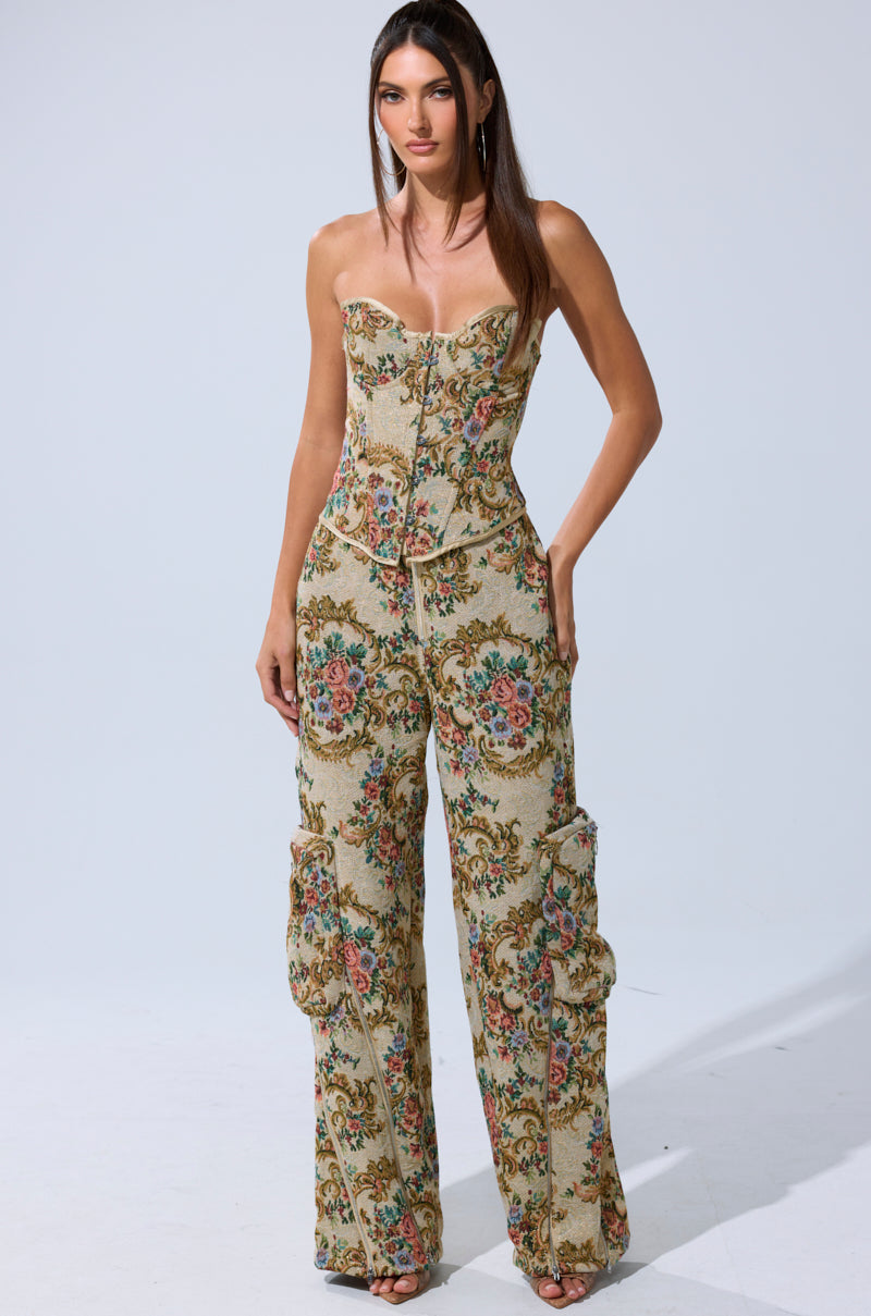 A woman wears a strapless, fitted corset top with SHINE AWAY BROCADE TROUSER, featuring a vintage floral tapestry pattern, cargo-style pockets, and a structured silhouette.