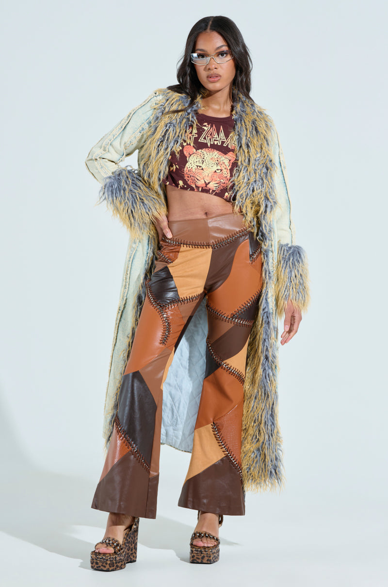 A person strikes a pose in a vibrant faux fur coat and graphic top, paired with TALK LATER PATCH FAUX LEATHER FLARE PANT. They rock leopard-print platform heels and sunglasses, standing confidently against a plain background. 1