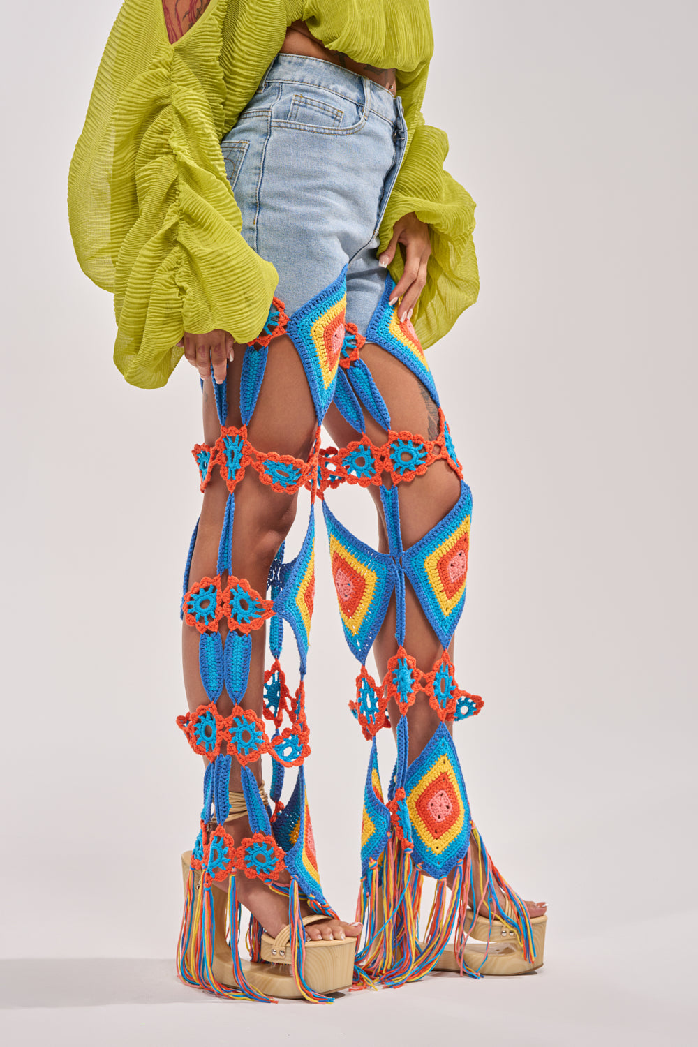 A person wears OUT OF OFFICE CROCHET DENIM JEANS with a lime green textured blouse and platform sandals with multicolored strings—finished with vibrant crochet accents for a playful festival-ready look. 2