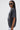 A woman models the KNOCK YOURSELF OUT DISTRESSED TEE—an acid-washed, metallic graphic shirt with chains—styled with oversized sunglasses and light plaid pants, standing sideways against a white background for a grungy-chic look.