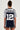 A person stands with their back to the camera, showcasing a sporty chic **SLICK JERSEY** that displays the text "ARCHIVES" on the upper back and the number "12" beneath it. This stylish jersey boasts a colorblock pattern in dark blue and silver. The individual has their hair up and is also wearing shorts.