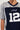 A person is wearing the SLICK JERSEY, a navy blue and gray football jersey with the number 12 on the front. This stylish piece boasts sports-inspired graphics and has "Nature silk" elegantly written in cursive above the number. The colorblock pattern adds a modern touch, though the person's face is not visible in the image.