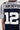 An individual wears the SLICK JERSEY, showcasing its sleek design with silver sleeves and a back featuring navy blue and white colors adorned with sports-inspired graphics. The word "ARCHIVES" is emblazoned at the top, while the large white number "12" boldly stands below.