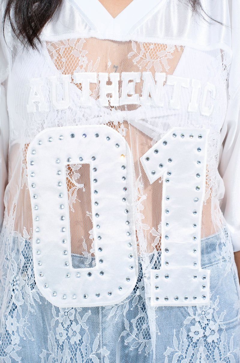 Close-up of the Charming Lace Jersey Dress, a white mesh top with floral lace details, showcasing "AUTHENTIC" and "01" in studs, capturing an oversized fit.