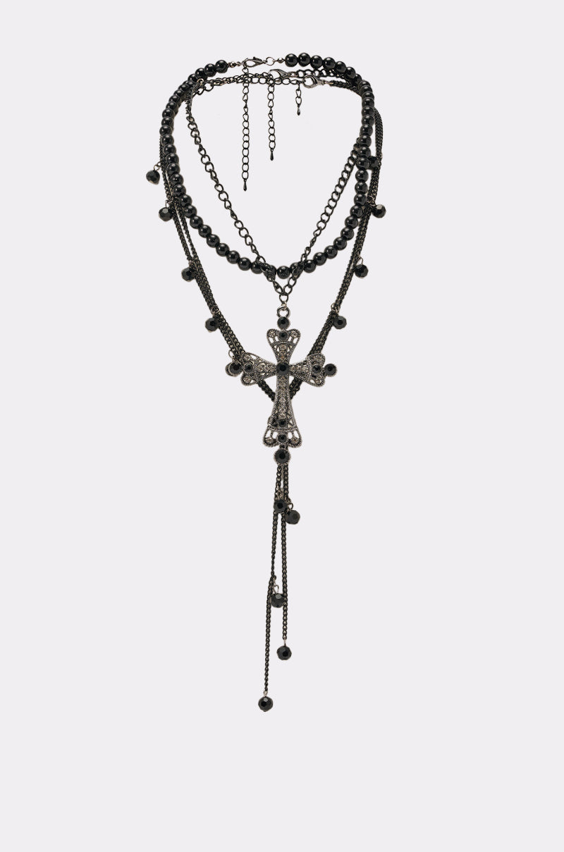 The TAKE CARE NECKLACE is a gothic layered black chain necklace with round beads, a large rhinestone cross pendant, dangling chains, and small beads. It features an adjustable clasp for the perfect fit. 0