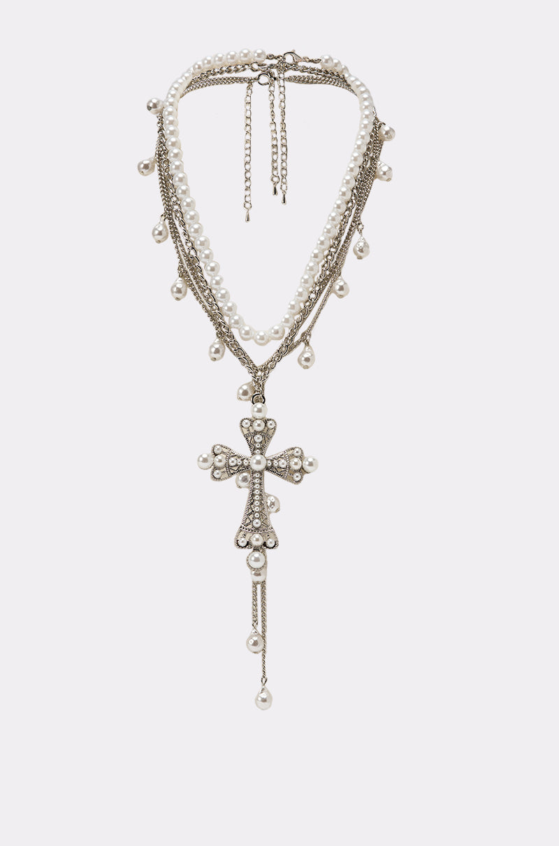 The PRINCESS PEARL NECKLACE features layered faux pearls and silver chains with a large rhinestone-studded pearl cross pendant, small pearl drops, and an adjustable clasp at the back. 0