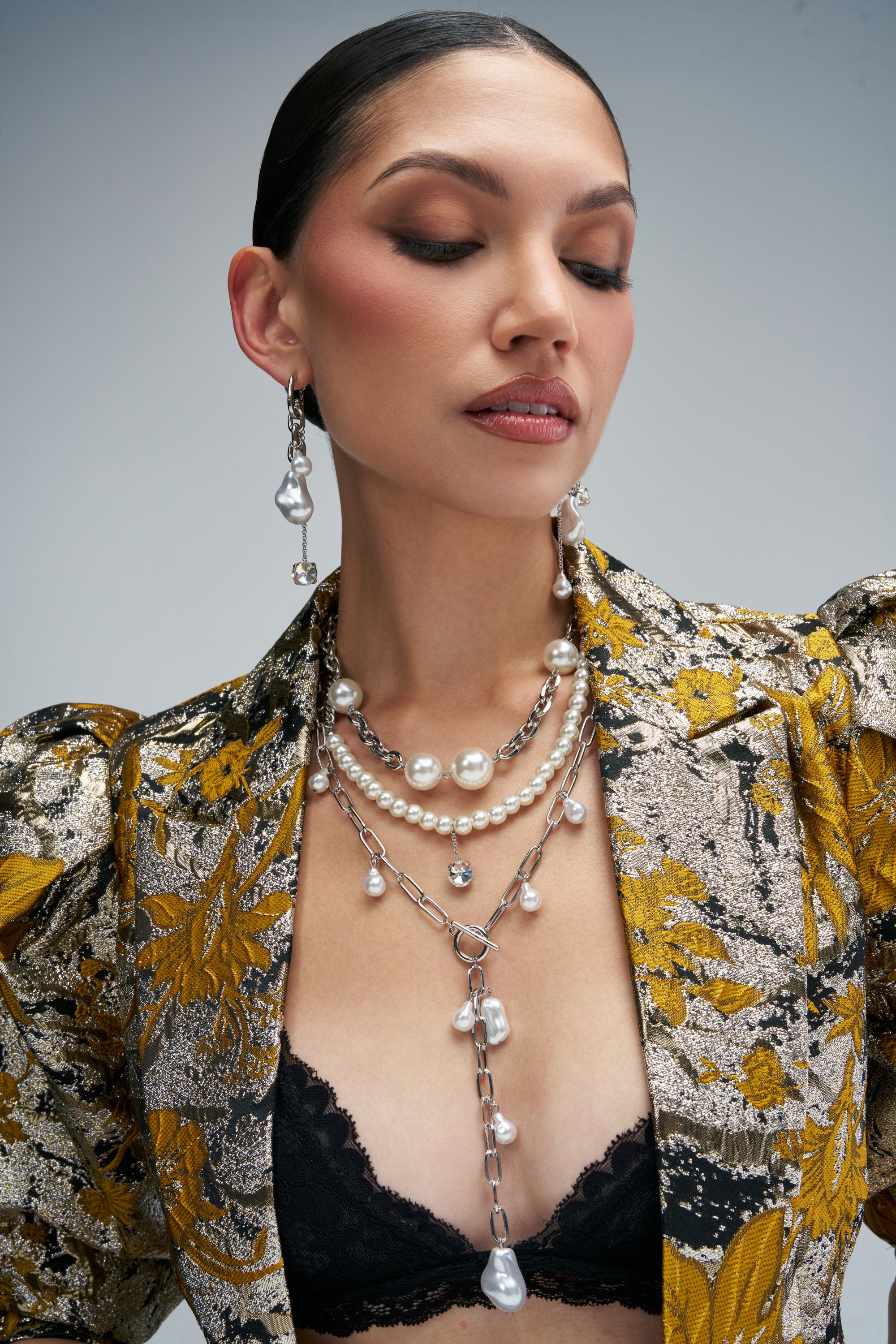 A model wears the IT GIRL PEARL LAYERED NECKLACE SET, a maximalist design featuring a mix of silver-tone chains, round white pearls, and irregular baroque pearls, paired with matching drop earrings.