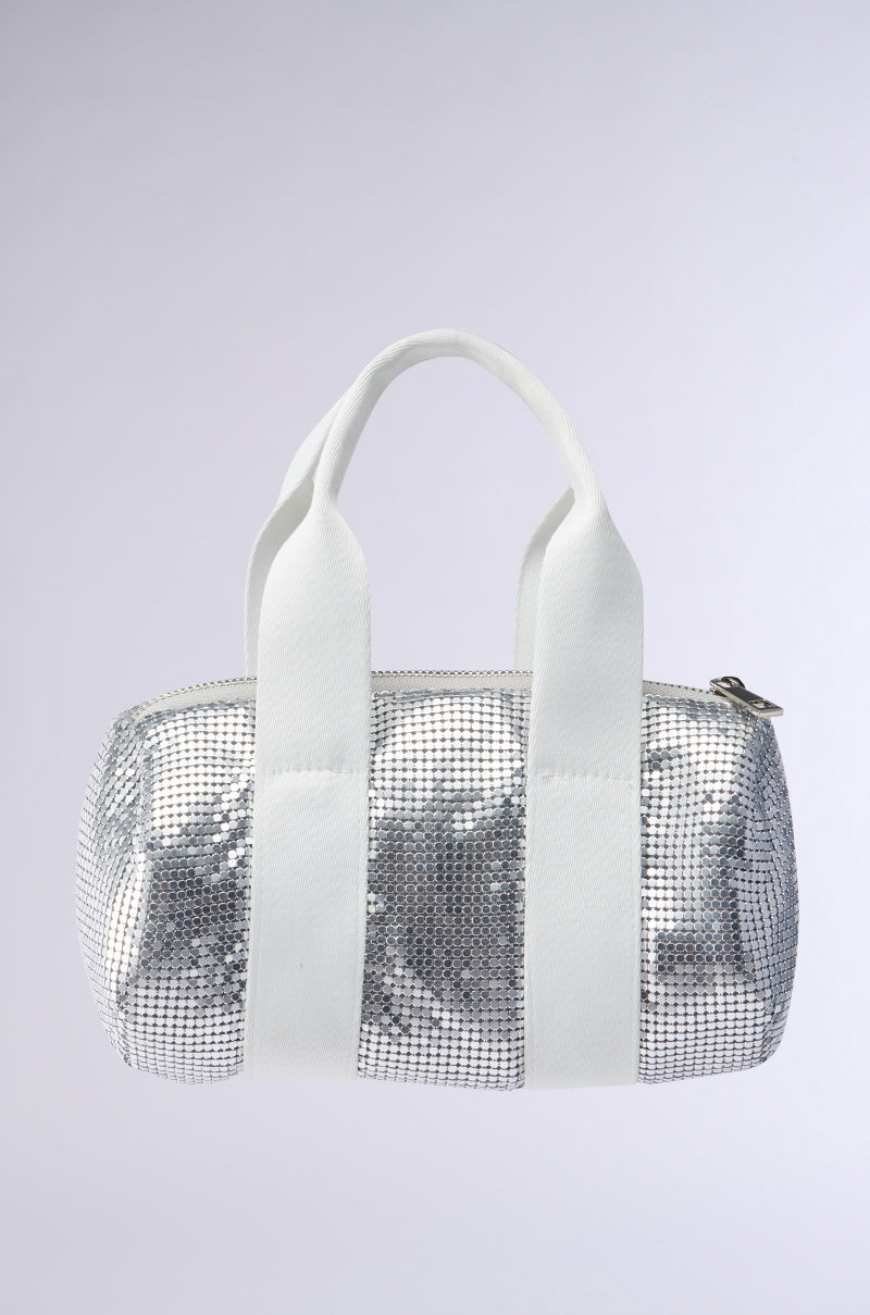 The TO THE DISCO CHAINMAIL PURSE is a small, cylindrical bag featuring a shimmering silver mesh exterior, white fabric handles, and a zipper closure, displayed against a plain light background.
