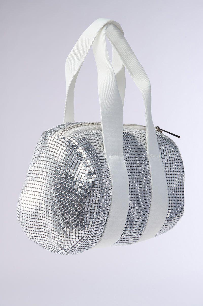 The TO THE DISCO CHAINMAIL PURSE is a compact, barrel-shaped handbag with shimmering silver sequins, white canvas handles, and a zipper closure, displayed against a plain light background.