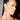 A woman with sleek, long dark hair in a high ponytail and dramatic makeup wears DRIP SEASON LONG DANGLE RHINESTONE EARRINGS as she poses against a neutral background, facing slightly to the right.