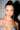 A woman with blue eyes and slicked-back dark hair wears the DRIP SEASON LONG DANGLE RHINESTONE EARRING and a sequin-embellished top, posing against a plain background with dramatic lighting that casts striking shadows.