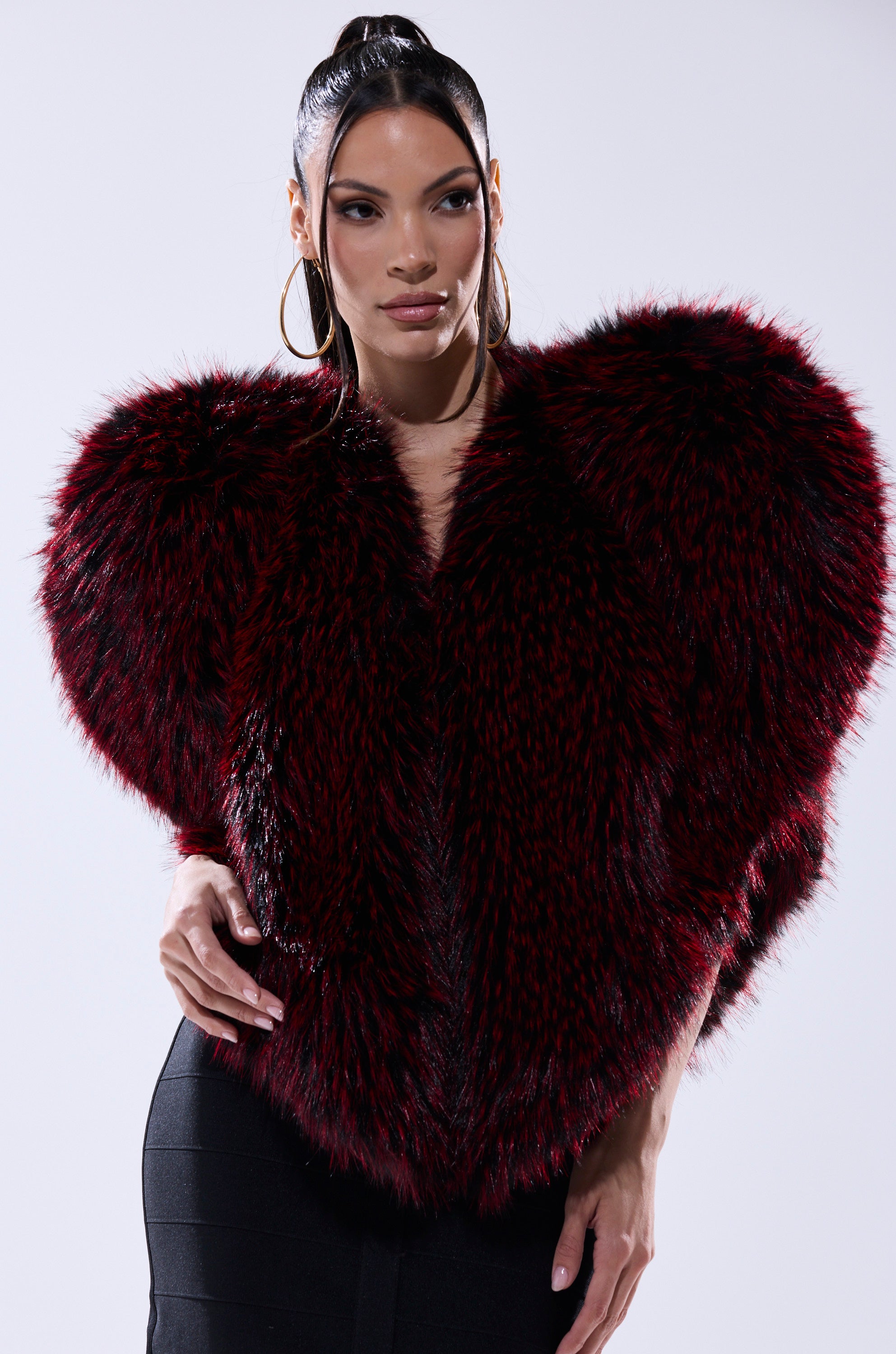 Wearing the STAR CROSSED LOVER FAUX FUR VEST in deep red and black, she exudes confidence, making this bold piece the highlight of her ensemble.