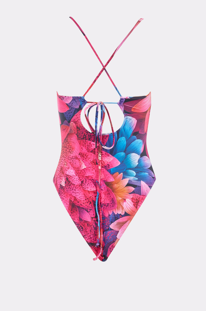 The IM RICH SWIMSUIT is a one-piece with vibrant pink, blue, orange, and purple floral patterns, crisscross straps, a cutout back, and tie closure. It is shown against a plain white background. 3