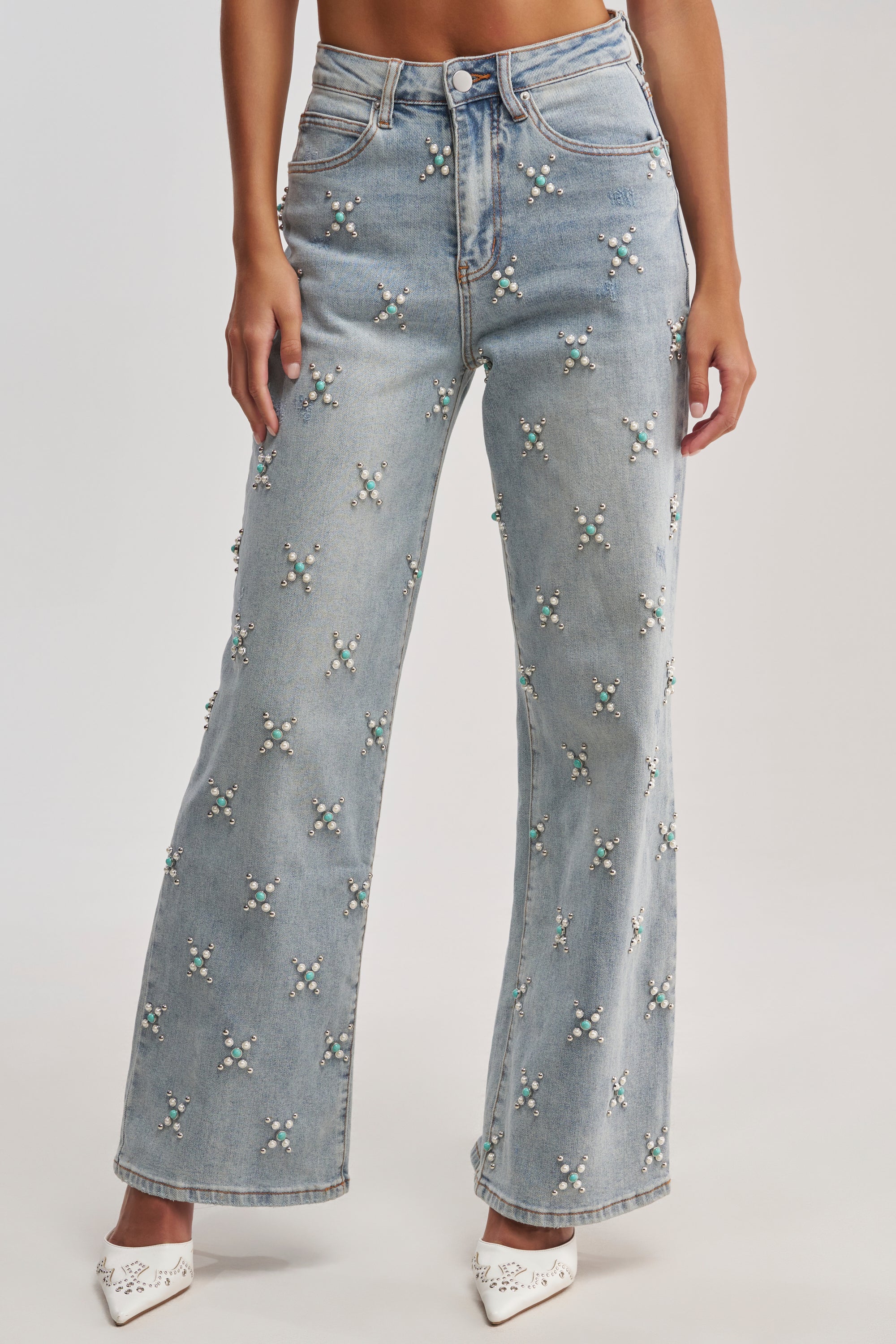 Wearing TRYING SOMETHING OUT STUDDED DENIM—light blue wide-leg jeans embellished with pearl and bead clusters—and white pointed-toe shoes. The image shows the outfit cropped from the waist down.