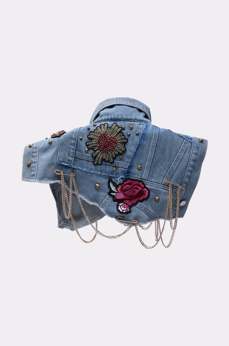 The STYLE ME UP DENIM COLLAR is a blue denim jacket featuring a classic collar, metal studs, embroidered sunflower and rose patches, plus gold chains draped across the back and sides.