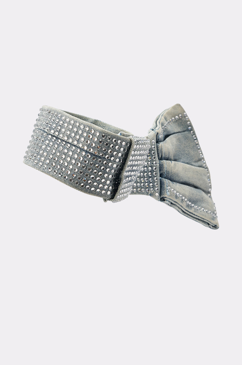 The WITH A BOW DENIM NECKLACE features denim-blue velvet adorned with rows of sparkling rhinestones and a large, elegant bow on one side, showcased against a plain white background. 3