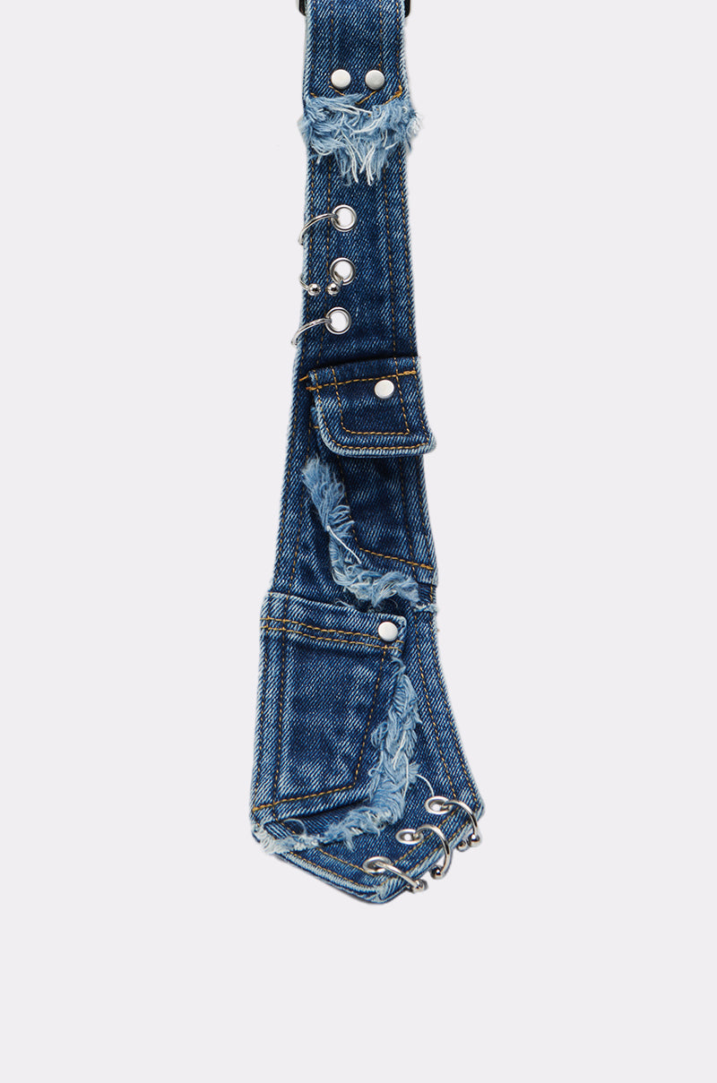 A close-up of the MIXED FEELINGS DENIM TIE, showcasing blue denim with frayed edges, silver grommets, exposed seams, snap buttons, and a small pocket against a plain white background.