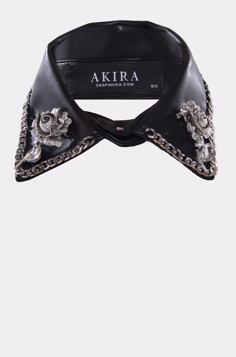 The GRACEY PU COLLAR NECKLACE features black faux leather with a detachable PU collar, silver chain trim, metallic floral and cherub embellishments on the sides, and an inner label marked "AKIRA. 1