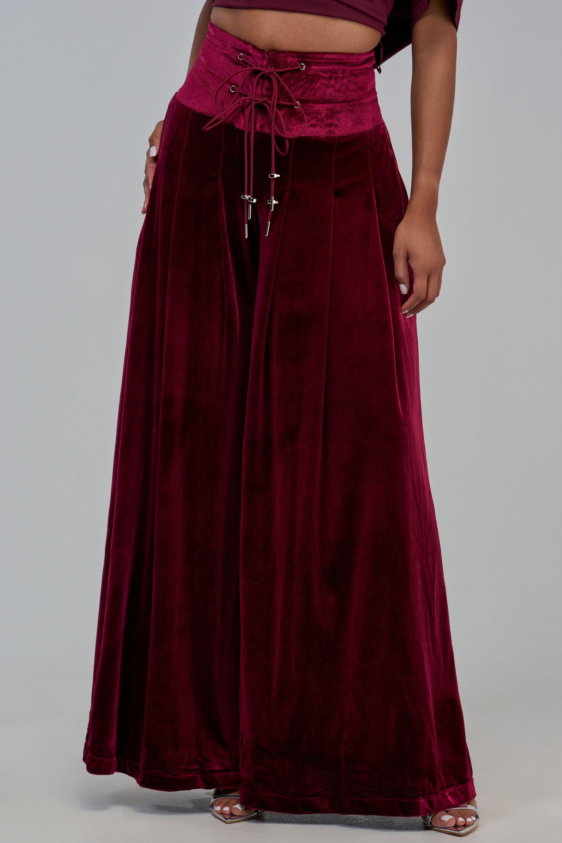 VALERIE VELVET PANT in deep red burgundy velvet, featuring a wide-leg silhouette and a high, lace-up corset-style waistband.