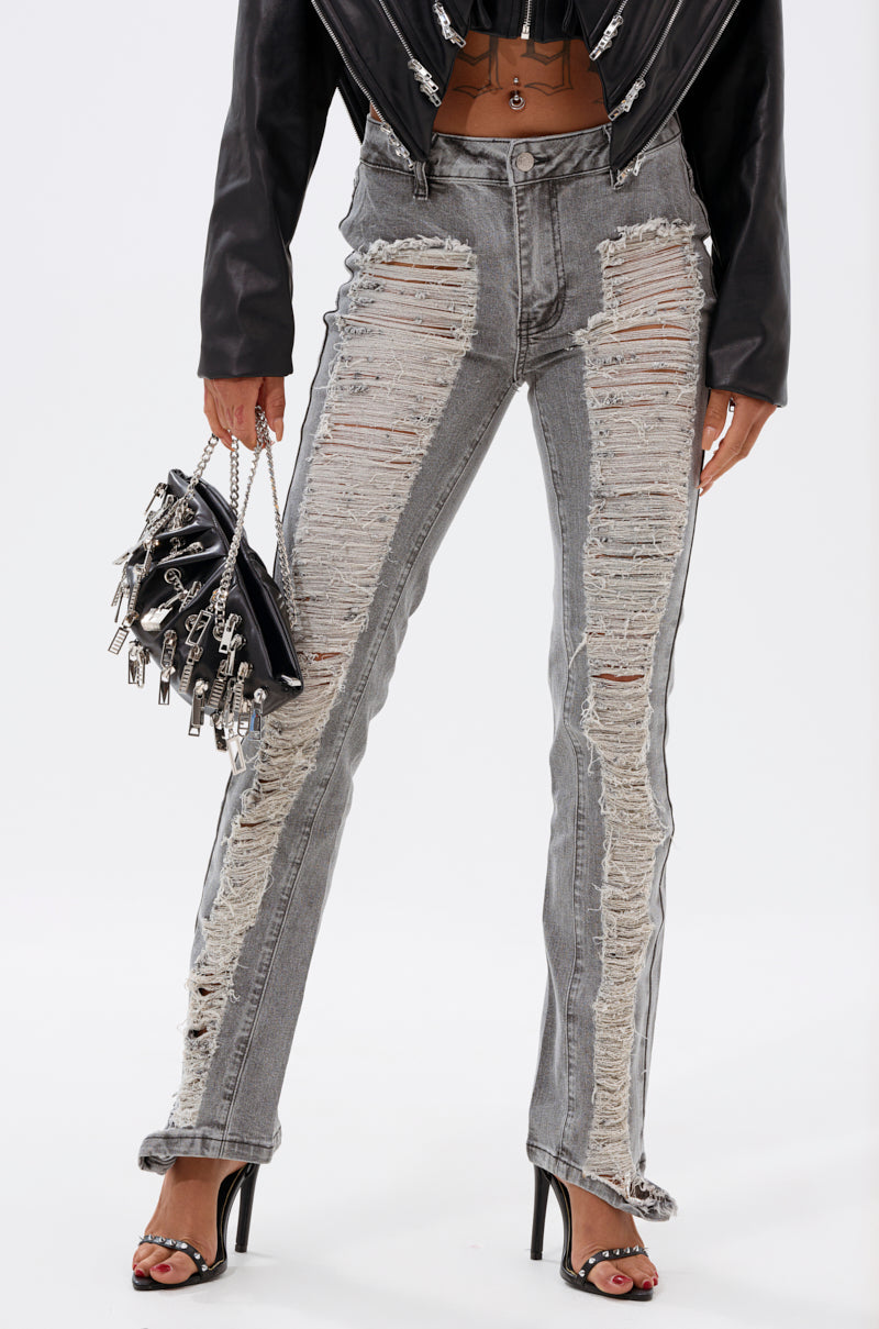 A person wears ULTRA DISTRESSED SKINNY DENIM with large front rips, a black leather jacket, black heeled sandals, and carries a black handbag with silver chains. 2