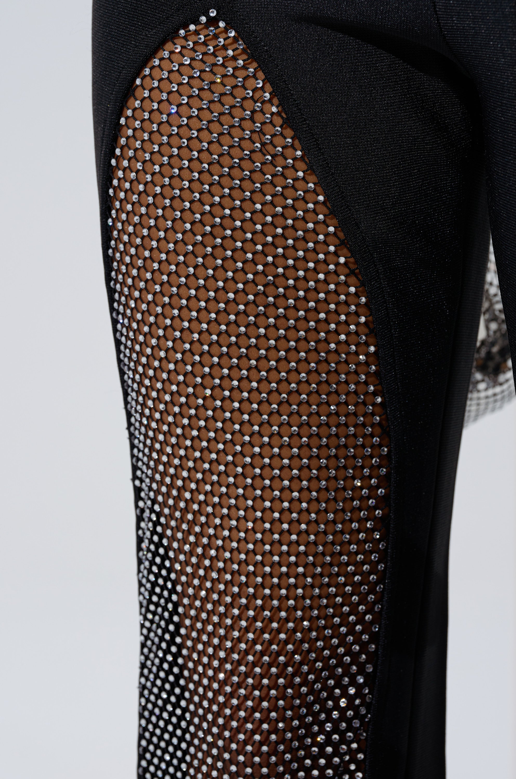 Close-up of JULIA BANDAGE TROUSER WITH MESH RHINESTONES, a high-waisted flared pant with a sheer mesh rhinestone panel that reveals some skin underneath.