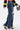 A woman styles the SPARKLE QUEEN WIDE-LEG DENIM—sparkly, high-waisted jeans with rhinestone details and a thigh rip—with a bold yellow striped long-sleeve top, heeled sandals, and a vibrant bag.