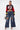 A woman stands confidently in SPARKLE QUEEN WIDE-LEG DENIM, a cropped “Tigers 24” football jersey, hoop earrings, high heels, and a colorful handbag against a plain white background.