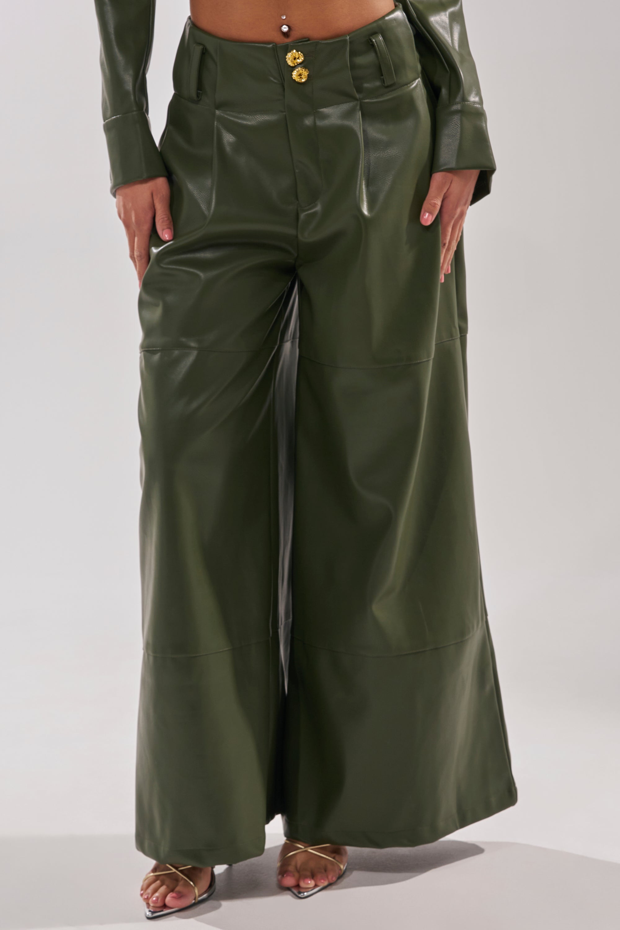 A person wears the REMEMBER YOU WIDE LEG TROUSER in olive green faux leather with a matching cropped jacket featuring gold buttons and open-toe heels. The image is cropped from the shoulders down. 1