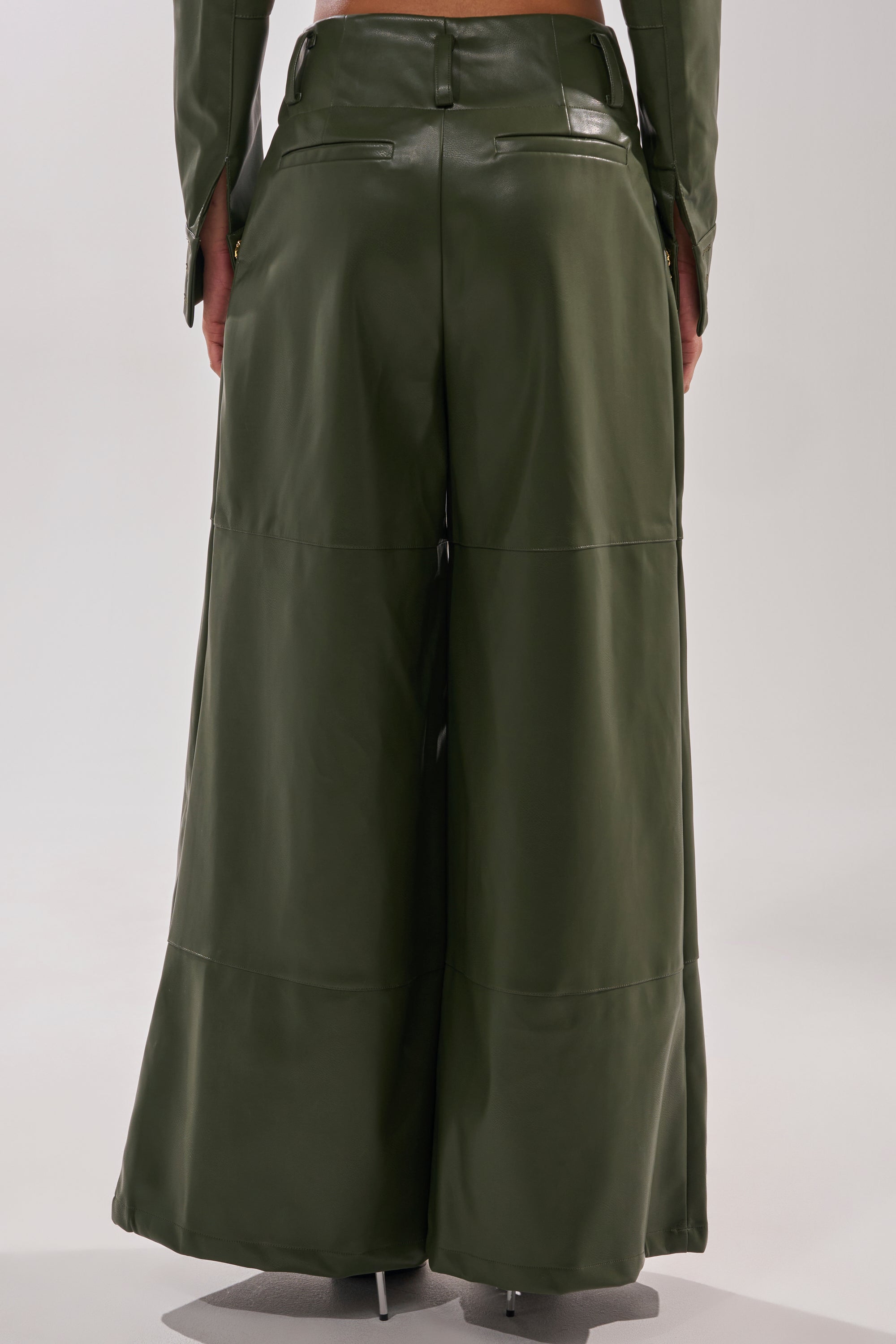 A person seen from the back wears the REMEMBER YOU WIDE LEG TROUSER in olive green faux leather, featuring high-rise fit and seam details, paired with a matching green top. 4