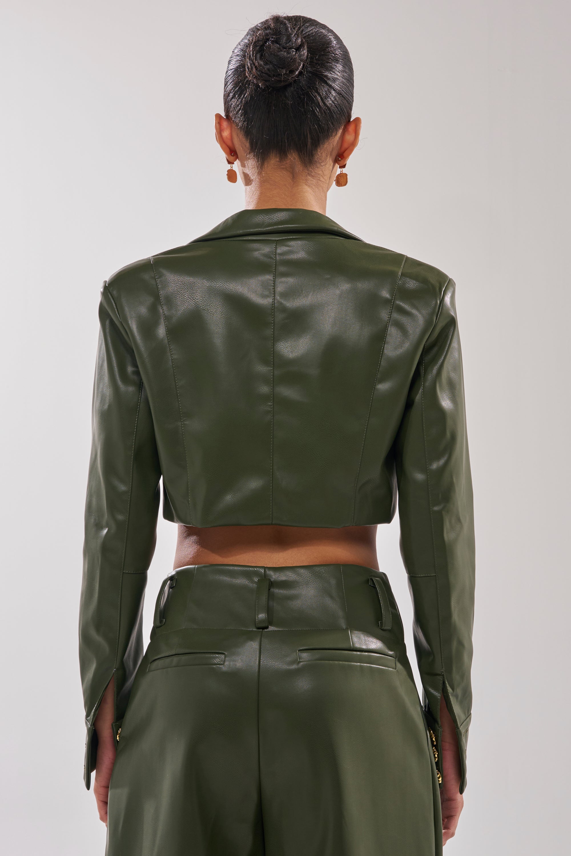 A person with dark hair in a neat bun is seen from behind, wearing the REMEMBER YOU CROPPED BLAZER in olive green, featuring gold button cuffs and clean lines for a modern, tailored look. 4