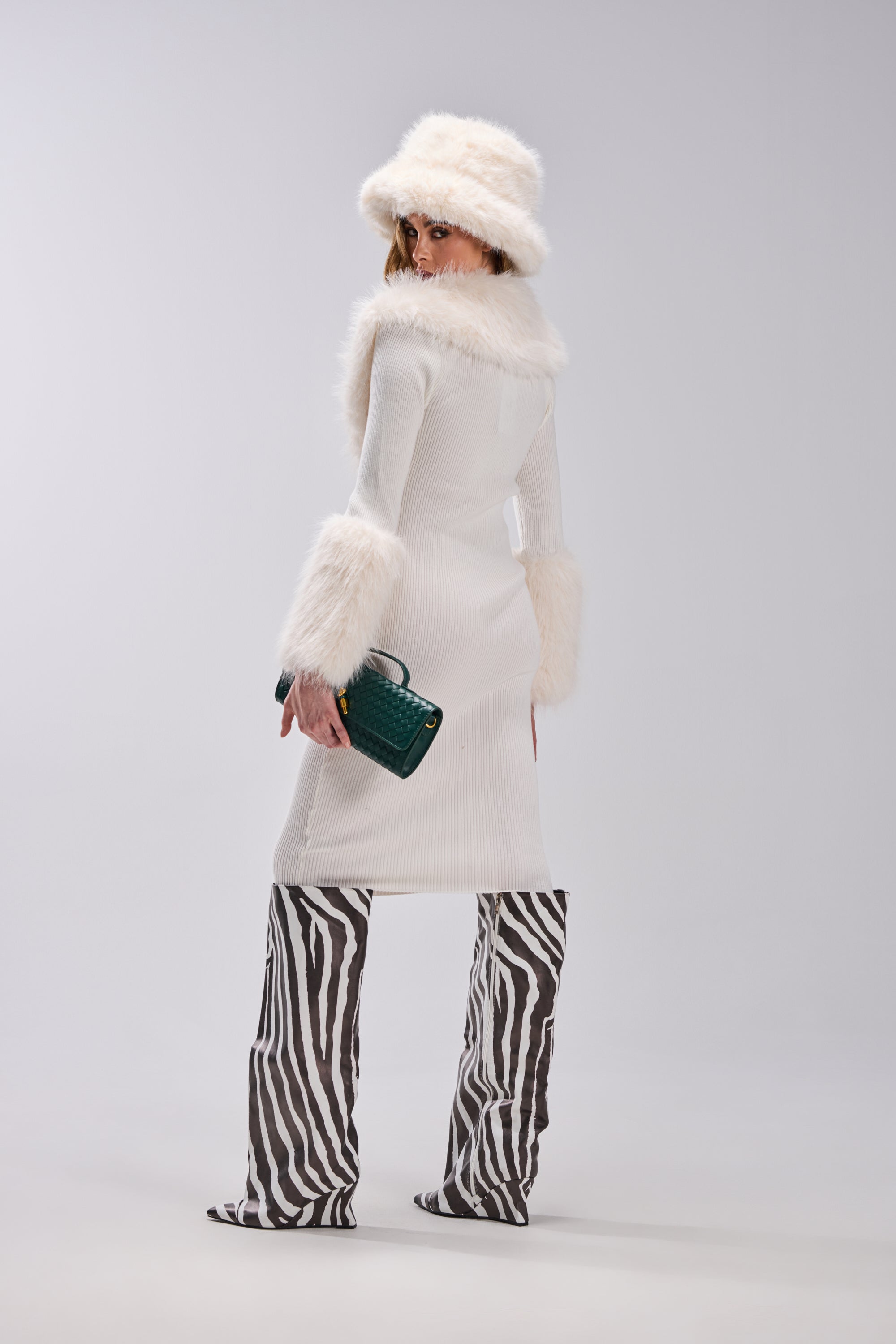 Wearing the CELINE SWEATER MIDI DRESS WITH FUR TRIM, a person stands facing away, looking over their shoulder against a plain background.