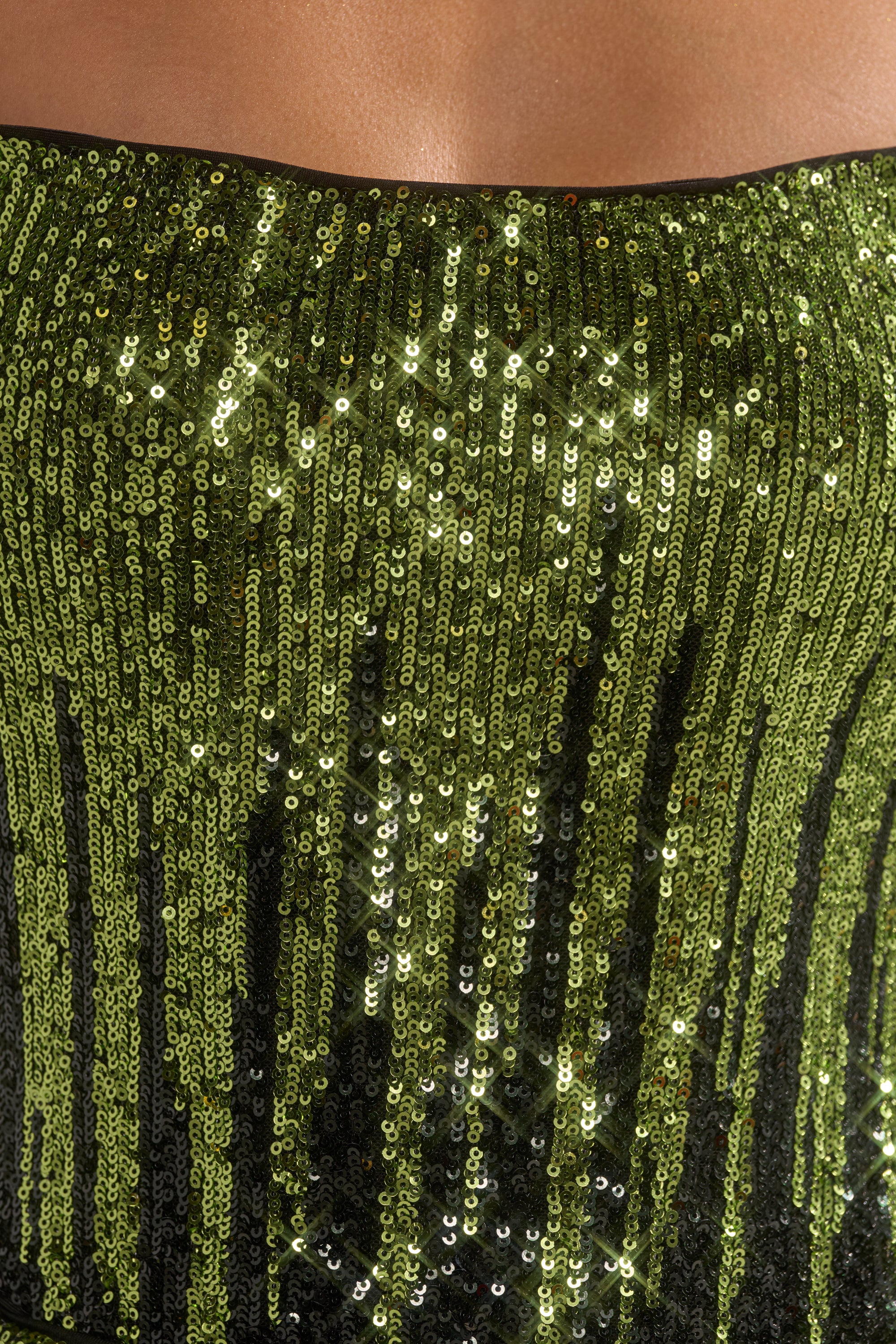 Close-up of a person wearing the SWEET THING SEQUIN CORSET, a strapless piece adorned with shiny green sequins in vertical lines that shimmer and catch the light.