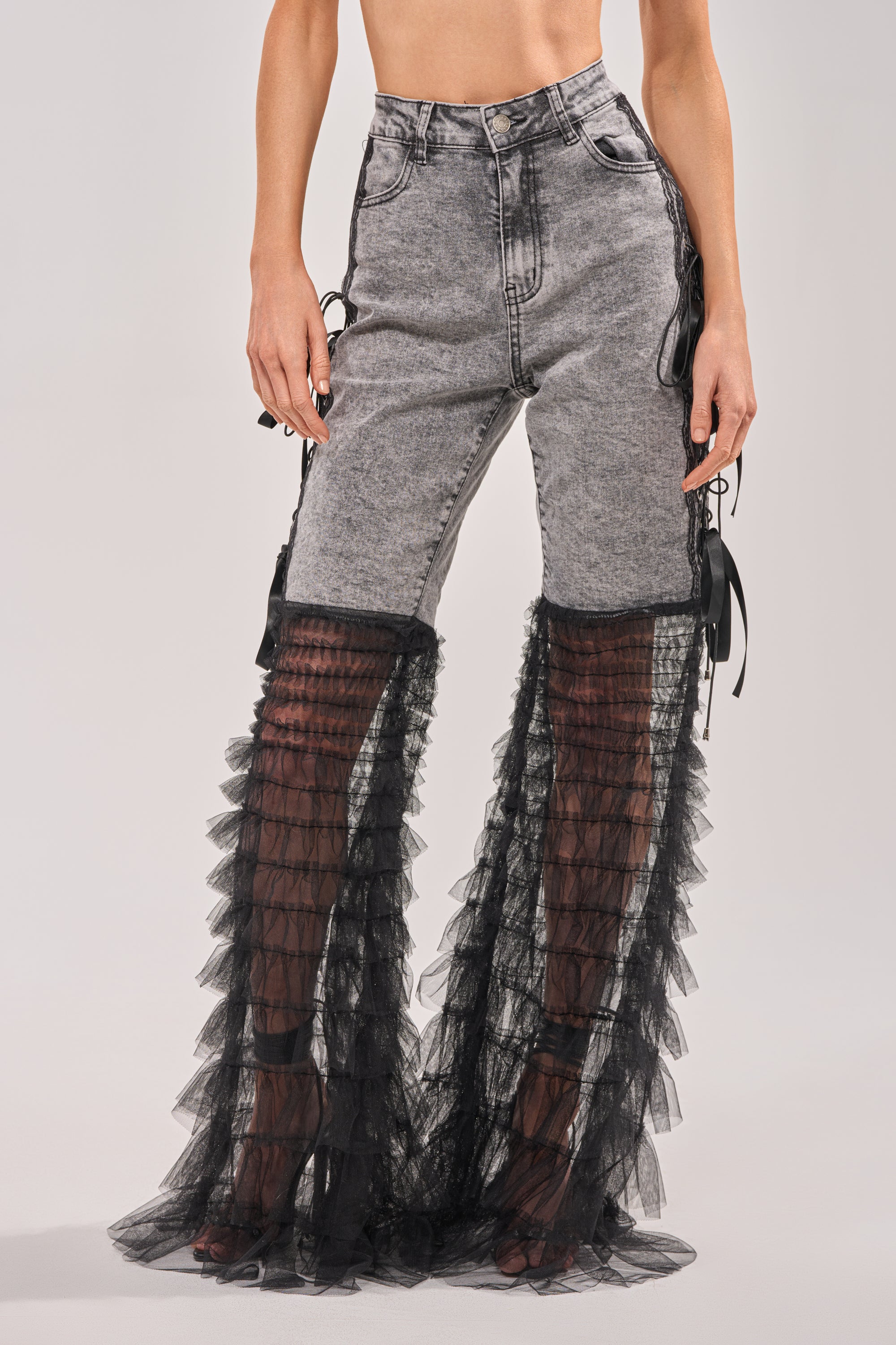 Wearing TICKED AND TIED LACE DETAIL FLARE DENIM: high-rise gray jeans with sheer black tulle panels from mid-thigh to ankle, revealing the legs for a striking, modern look with standout lace details. 1