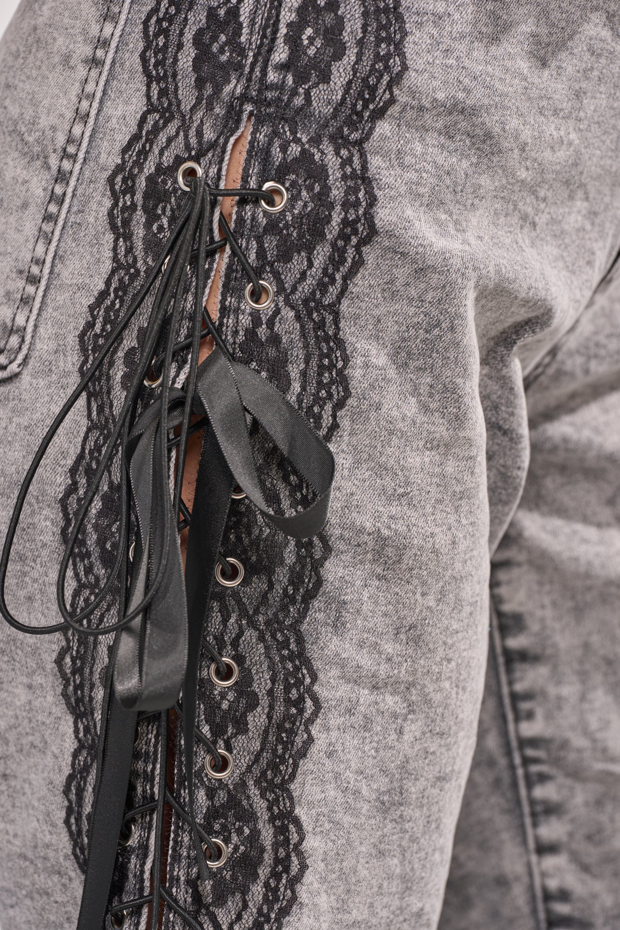 Close-up of the TICKED AND TIED LACE DETAIL FLARE DENIM, showcasing high-rise flare jeans with black lace trim and ribbon lacing along the side seam for a decorative, stylish accent. 6