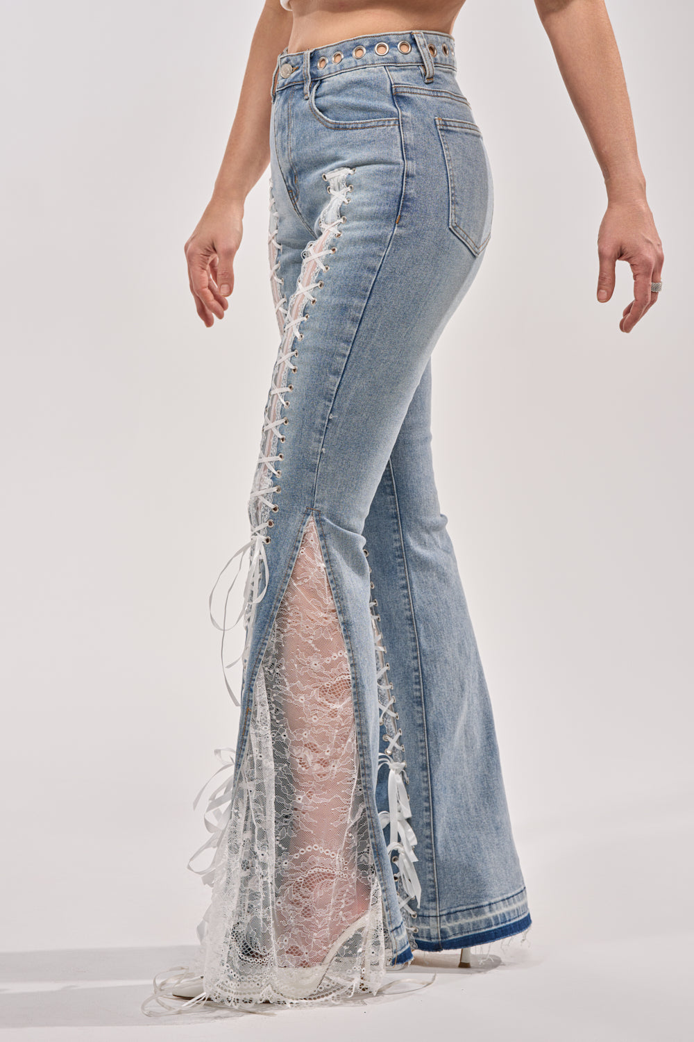 Wearing the LOVE ME LIKE THAT LACE UP FLARE DENIM, featuring a high-rise waist, flared legs with white lace inserts, lace-up ribbon panels along the sides that reveal skin beneath, and bold grommet details at the waistband. 4