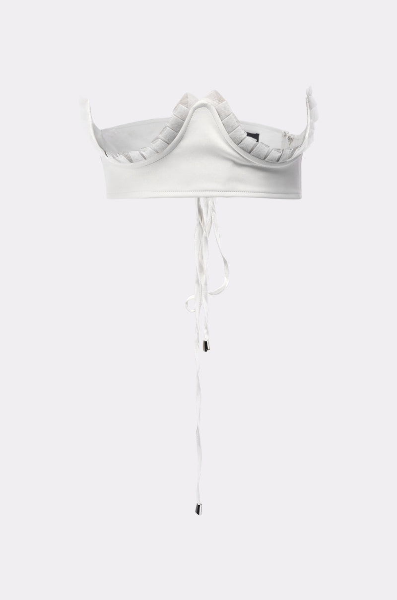 The RUFFLE ME TO IT UNDERBUST BELT is styled with a white, structured headpiece featuring pleated edges and long center ties, all set against a plain light gray background. 2