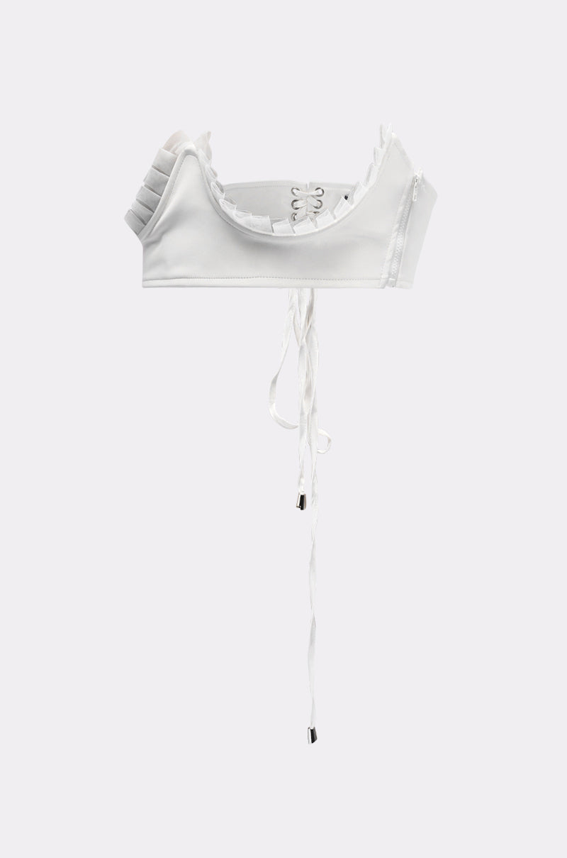 The RUFFLE ME TO IT UNDERBUST BELT is showcased over a white crop top with ruffled shoulders, lace-up front ties, and a structured fit, set against a plain light grey background. 4