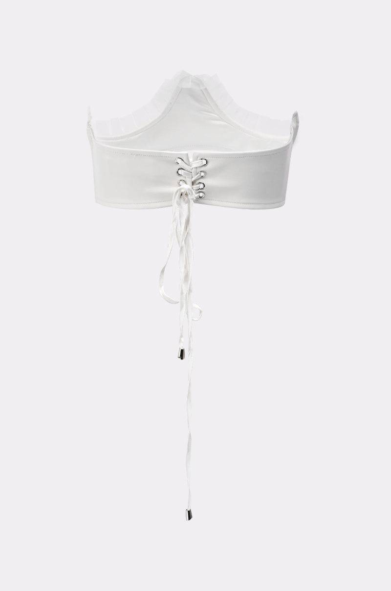 A white crop top with a high neckline and lace-up front featuring silver eyelets pairs perfectly with the RUFFLE ME TO IT UNDERBUST BELT for a sleek, structured look against a plain light background. 5