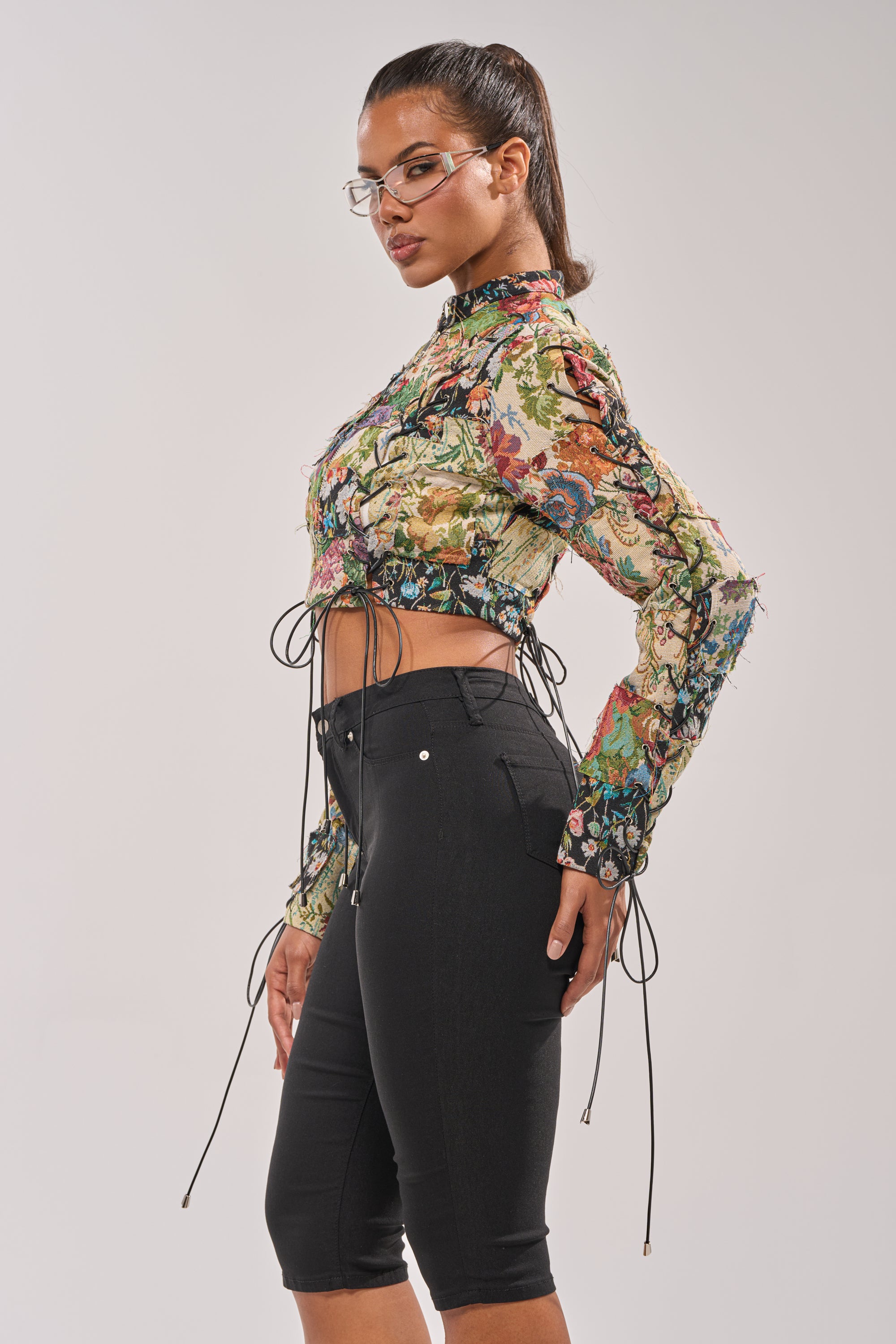 A woman with a high ponytail and clear glasses wears the TELL ME ABOUT IT PATCHWORK MOTO, posing sideways against a plain background. 4