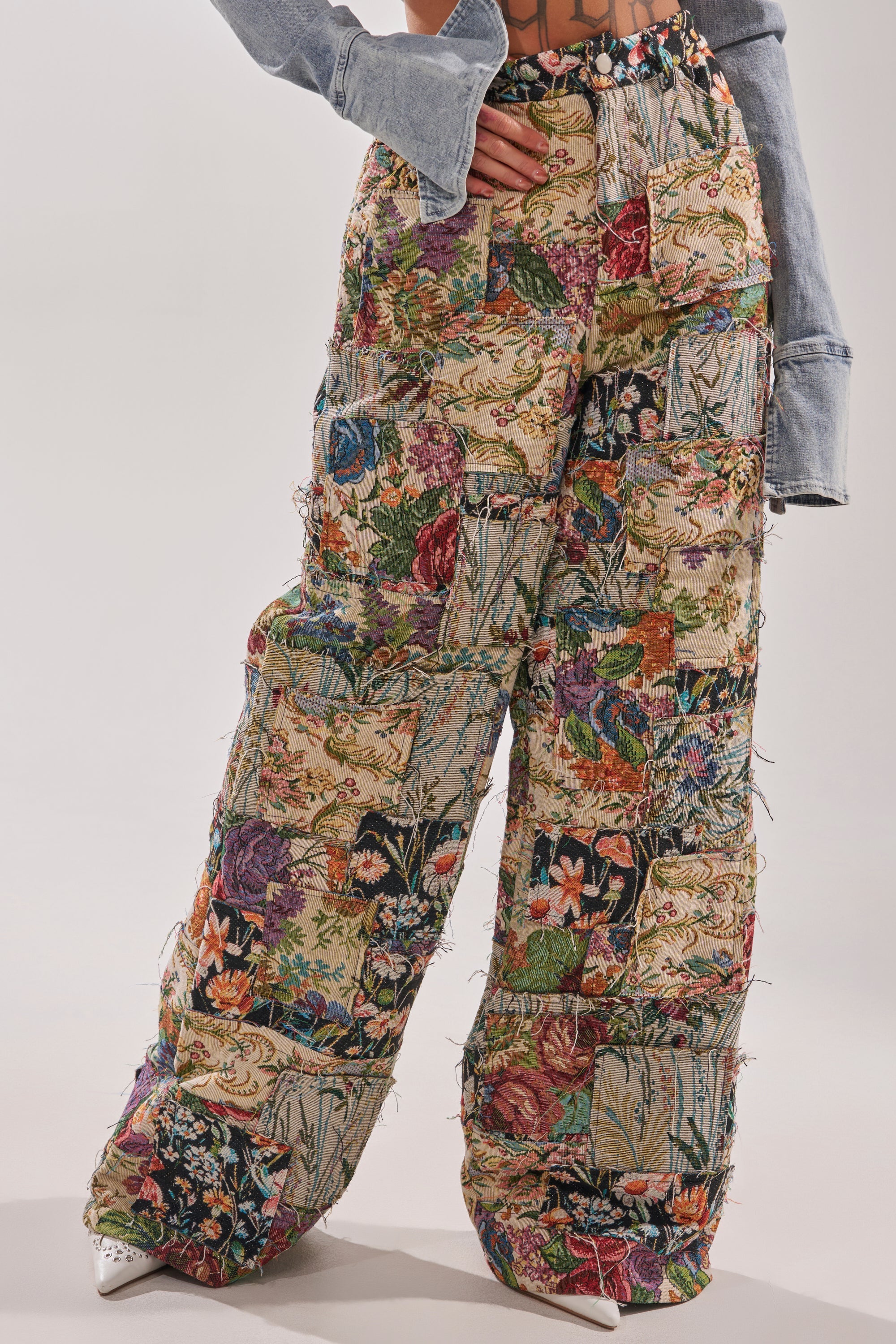 Wearing the OUT OF MY MIND TAPESTRY PANT—high-waisted, vintage-inspired patchwork floral pants with a colorful quilted texture—paired with a flared-sleeve light blue denim top and white pointed shoes for a vibrant look. 1