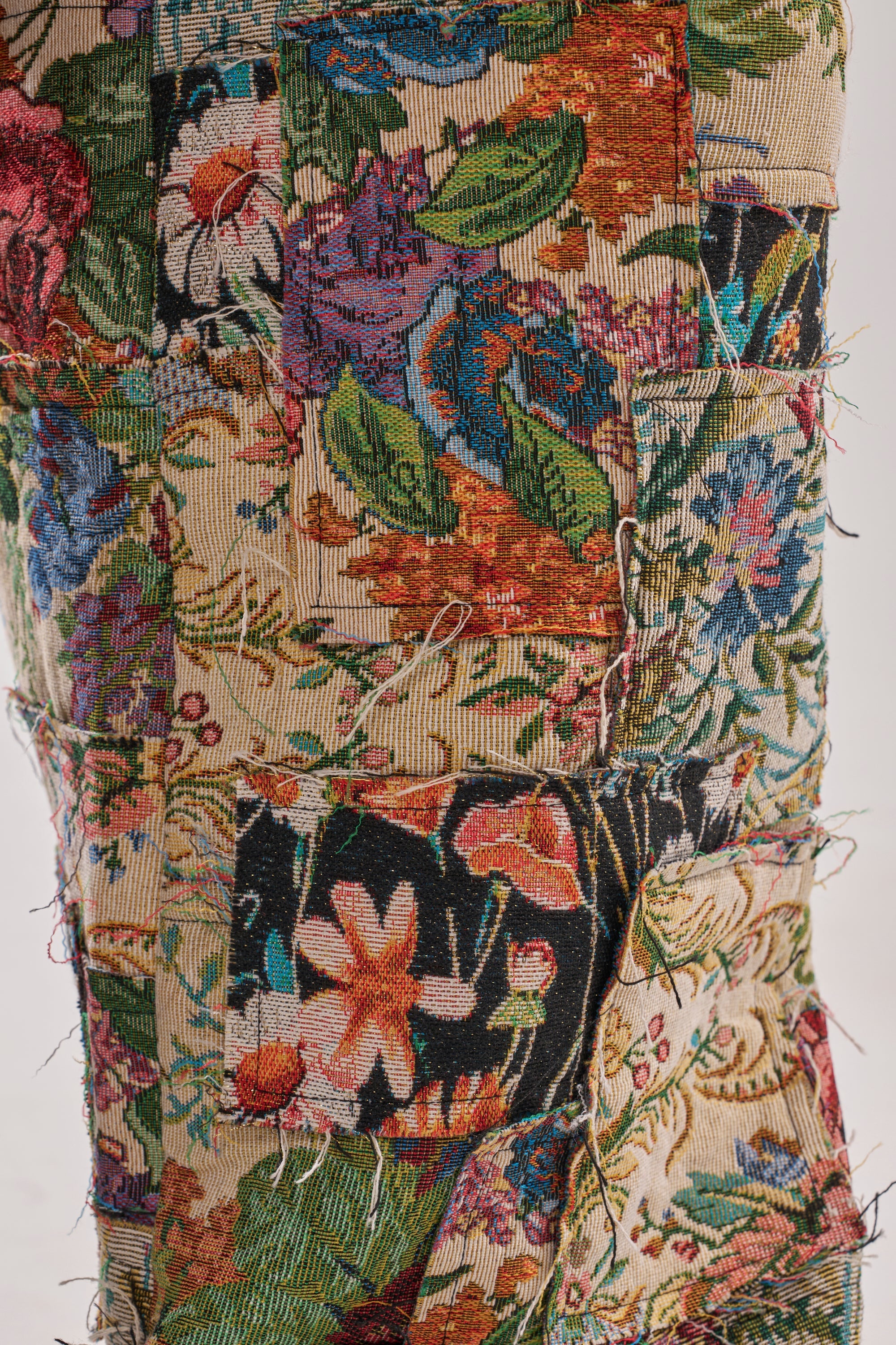 A close-up of the OUT OF MY MIND TAPESTRY PANT, featuring colorful tapestry fabric patches sewn with visible stitches and frayed edges for a textured, vintage-inspired look. 7