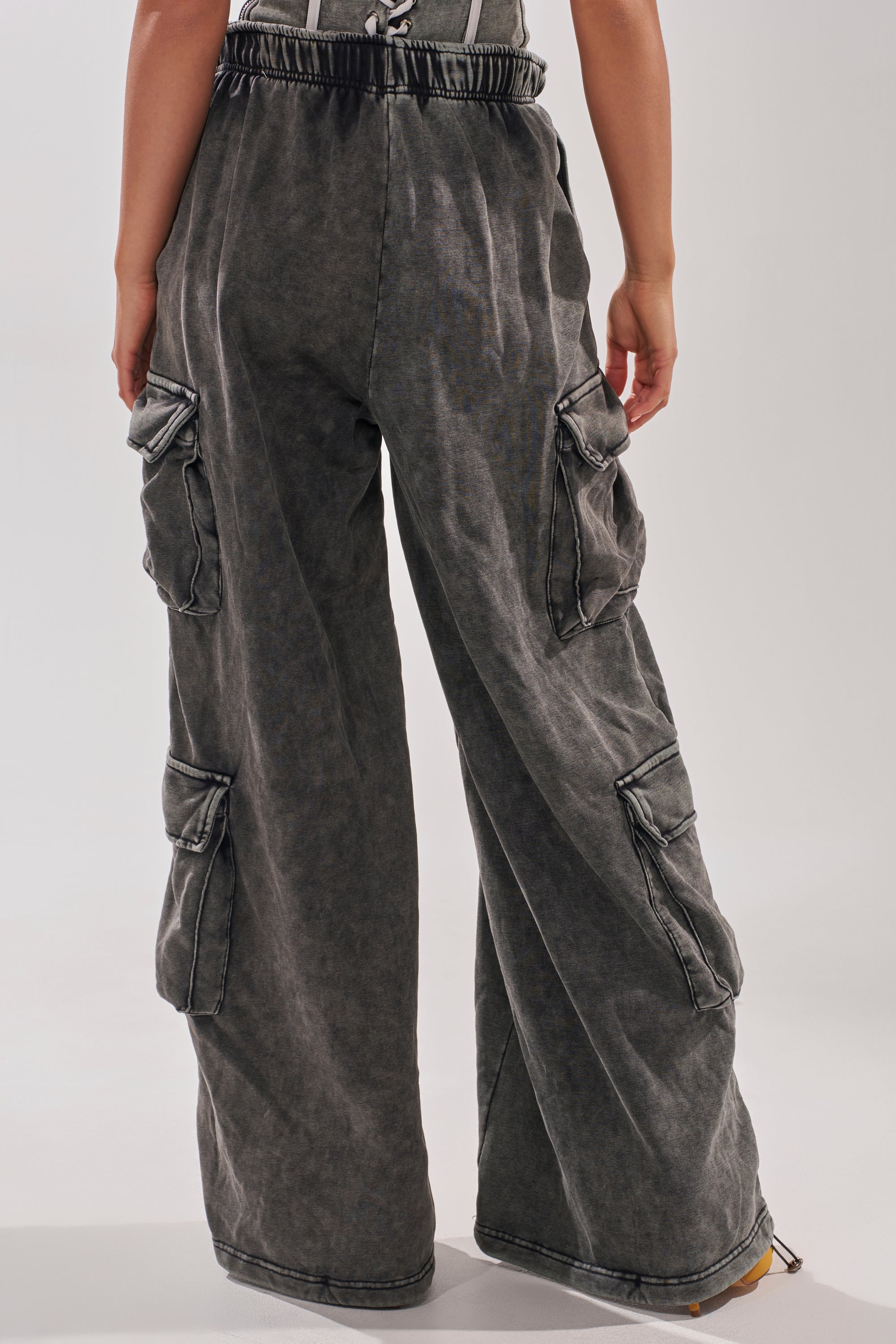 Person wearing ROCK AND ROLL WIDE LEG JOGGER pants in dark gray, seen from the back. These loose-fit joggers feature an elastic waistband, multiple side pockets, visible seams, and a wide-leg silhouette against a plain light background. 4