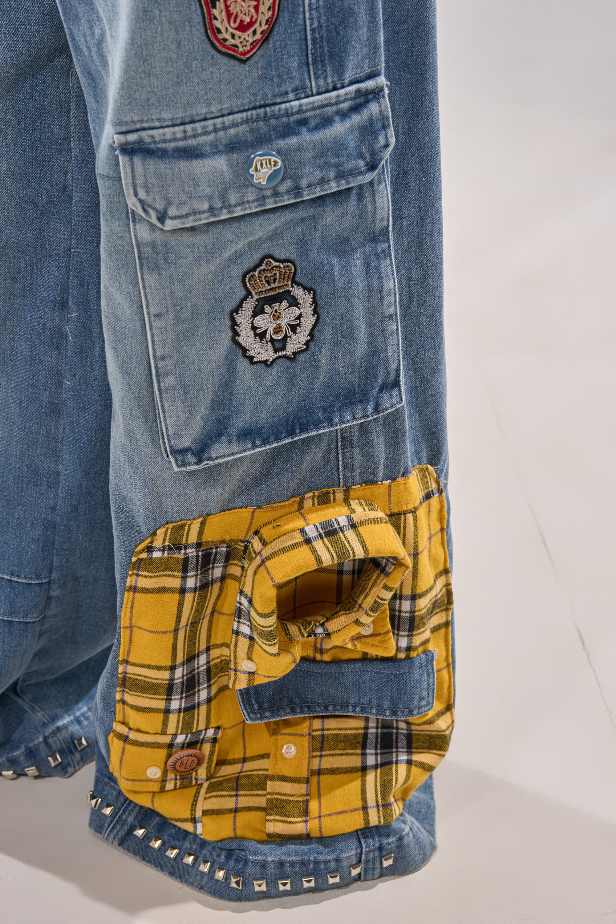 Close-up of FEELING THE WAVES RELAXED DENIM: blue jeans with decorative patches and a yellow plaid mini-shirt applique featuring buttons and a pocket sewn onto the leg. 8