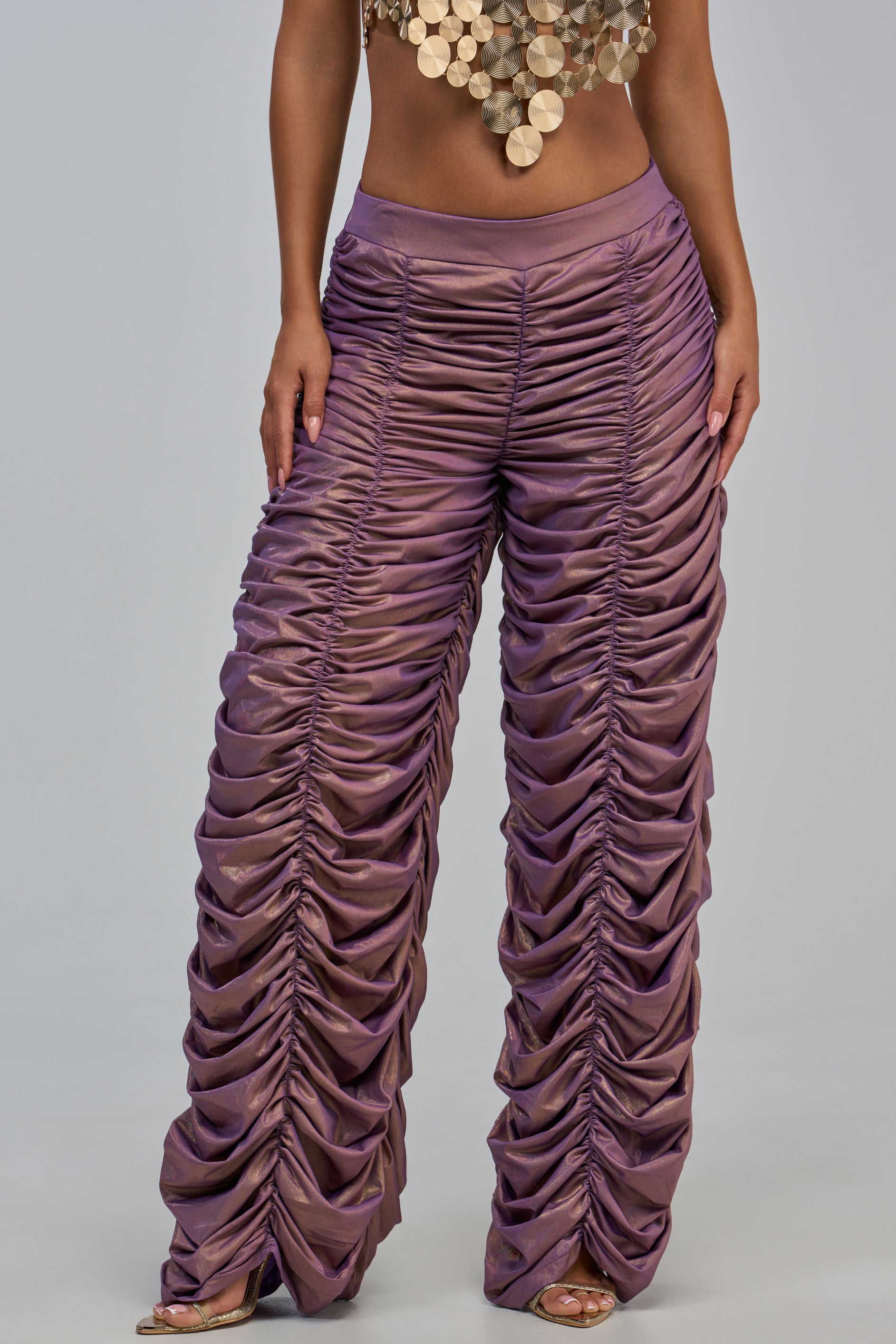 Wearing the WOW WOW WOW RUCHED PANT, a high-waisted, wide-leg statement pant in ruched lavender with a shiny metallic finish, paired with a gold statement crop top.
